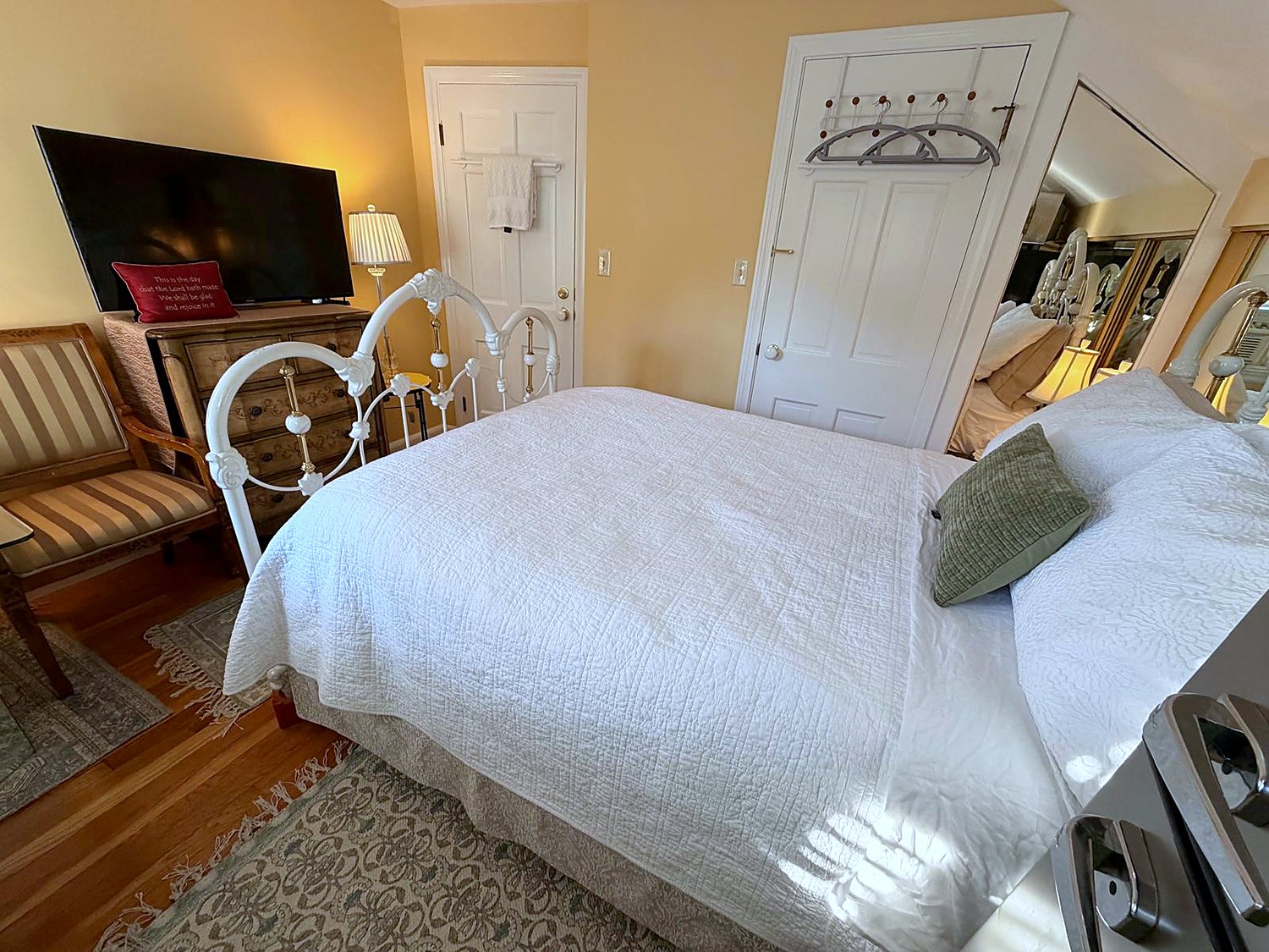 The Royalty Room at Wellesley Boutique Inn, with a full-size white iron bed and television