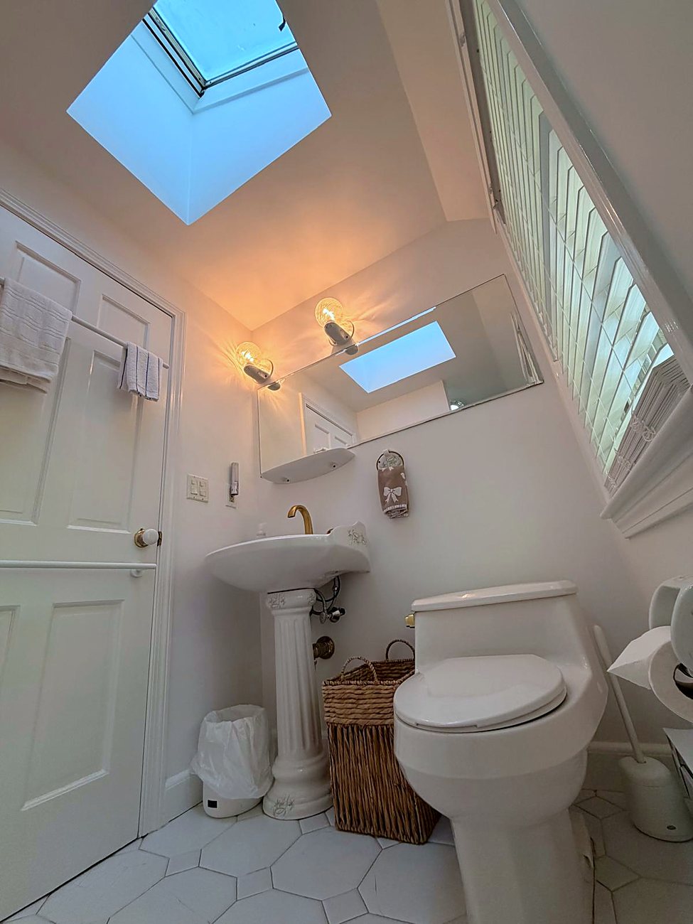 Shared guest bathroom with skylight and pedestal sink at Wellesley Boutique Inn